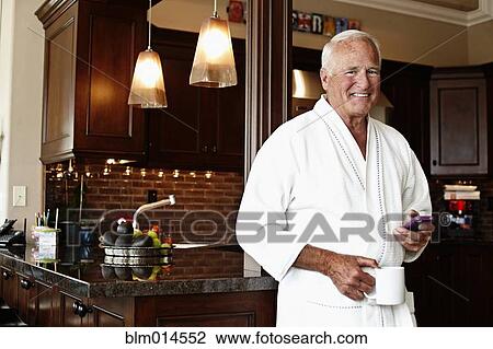 Stock Image - Caucasian man in robe using cell phone. Fotosearch