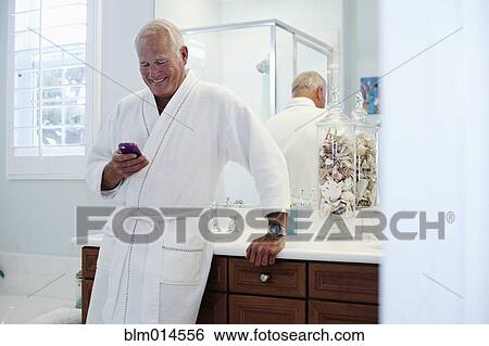 Stock Photograph - Caucasian man in robe using cell phone. Fotosearch