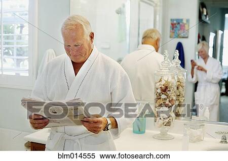 Stock Photography - Caucasian man reading newspaper in bathroom. Fotosearch