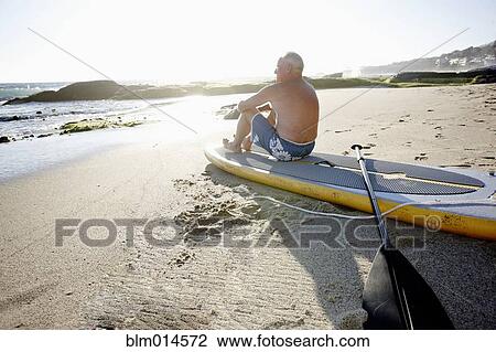 Caucasian man sitting on paddleboard View Large Photo Image Stock Image - Caucasian man sitting on paddleboard. Fotosearch