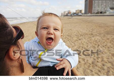 Caucasian mother holding baby boy on beach View Large Photo Image Stock Photo - Caucasian mother holding baby boy on beach. Fotosearch