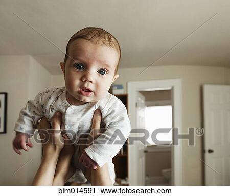 Stock Image - Caucasian mother lifting baby boy. Fotosearch