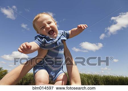 Stock Photo - Caucasian mother lifting baby boy. Fotosearch