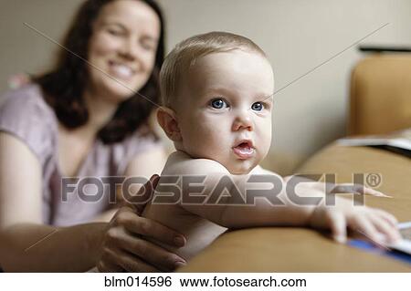 Stock Photograph - Caucasian mother supporting baby boy. Fotosearch