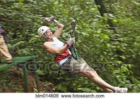 Stock Photo - Caucasian woman on zip line in forest. Fotosearch