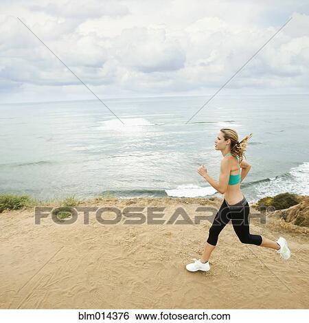 Stock Photograph - Caucasian woman running on beach. Fotosearch