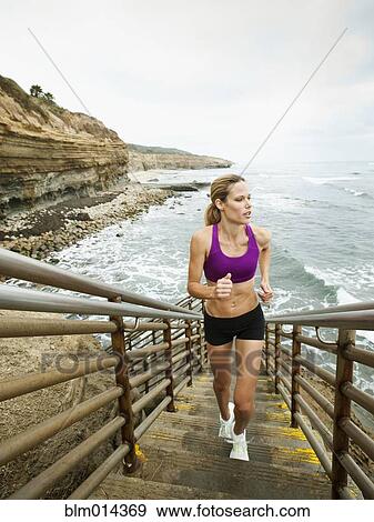 Caucasian woman running up stairs next to ocean View Large Photo Image Stock Photo - Caucasian woman running up stairs next to ocean. Fotosearch