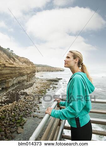 Stock Image - Caucasian woman standing near ocean. Fotosearch