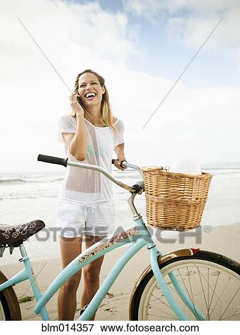Stock Photo - Caucasian woman using cell phone on beach. Fotosearch