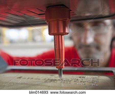 Stock Image - Caucasian worker using branding machine in factory. Fotosearch