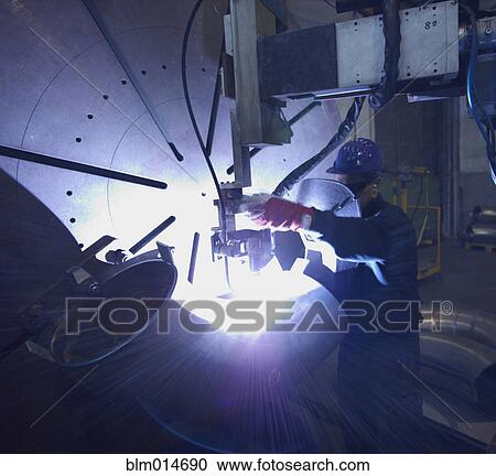Stock Image - Caucasian worker working on steel pipe in factory. Fotosearch