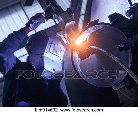 Stock Image - Caucasian worker working on steel pipe in factory. Fotosearch