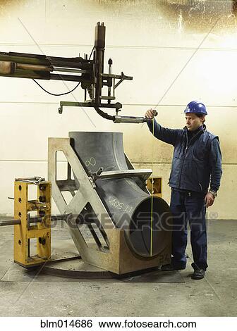 Stock Photograph - Caucasian worker working on steel pipe in factory. Fotosearch