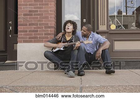 Father watching son playing electric guitar View Large Photo Image Stock Photograph - Father watching son playing electric guitar. Fotosearch