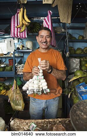 Hispanic man holding garlic in shop View Large Photo Image Stock Image - Hispanic man holding garlic in shop. Fotosearch