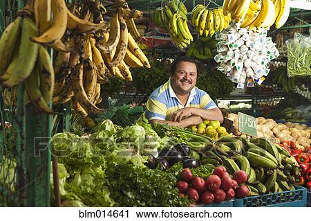 Stock Image - Hispanic man working in produce shop. Fotosearch
