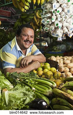 Stock Image - Hispanic man working in produce shop. Fotosearch