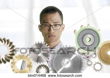 Stock Photo - Korean man standing with gears. Fotosearch
