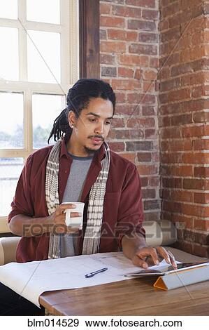 Stock Photo - Mixed race man using digital tablet in coffee shop. Fotosearch