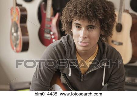 Stock Photography - Mixed race teenager sitting with guitars. Fotosearch