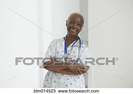 Stock Image - Smiling Black nurse leaning on wall. Fotosearch