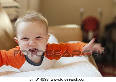 Stock Image - Smiling Caucasian baby boy laying on sofa. Fotosearch