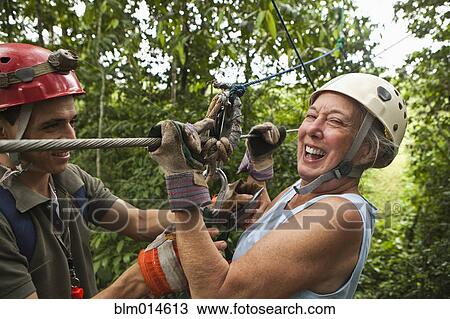 Woman being helped onto zip line View Large Photo Image Stock Image - Woman being helped onto zip line. Fotosearch