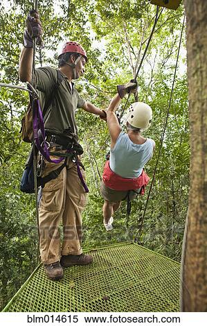 Stock Photography - Woman being helped onto zip line. Fotosearch