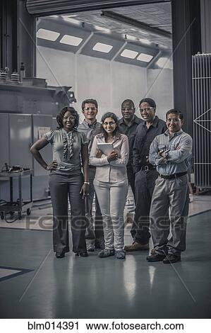 Workers standing together in factory View Large Photo Image Stock Image - Workers standing together in factory. Fotosearch