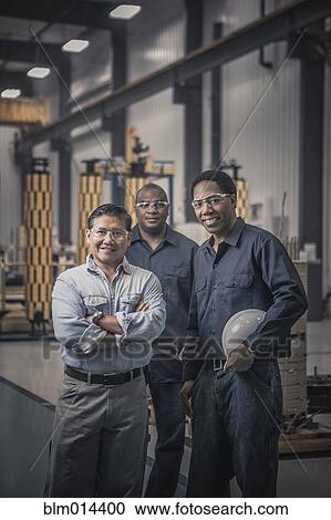 Workers standing together in factory View Large Photo Image Stock Image - Workers standing together in factory. Fotosearch