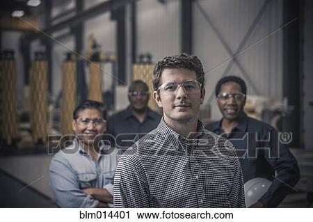 Stock Image - Workers standing together in factory. Fotosearch