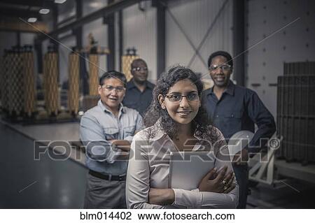 Stock Image - Workers standing together in factory. Fotosearch