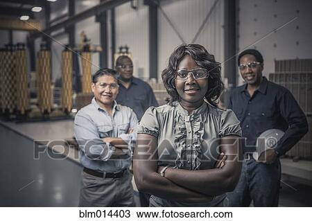 Stock Image - Workers standing together in factory. Fotosearch