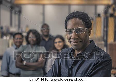 Stock Image - Workers standing together in factory. Fotosearch