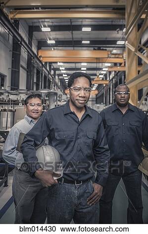 Workers standing together in factory View Large Photo Image Stock Image - Workers standing together in factory. Fotosearch