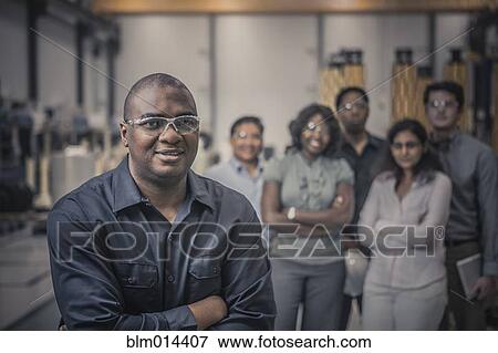 Stock Photo - Workers standing together in factory. Fotosearch