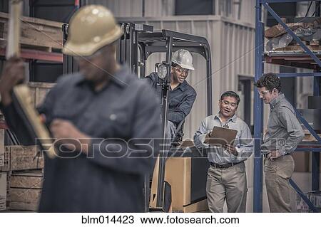 Stock Image - Workers talking together in factory. Fotosearch
