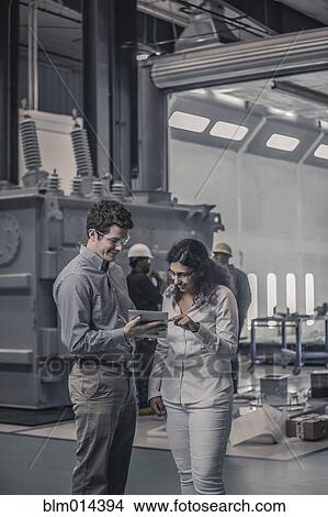 Workers using digital tablet together in factory View Large Photo Image Picture - Workers using digital tablet together in factory. Fotosearch
