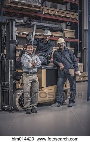 Stock Image - Workers with forklift in factory. Fotosearch
