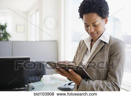 Stock Photo - African American businesswoman using digital tablet in office. Fotosearch