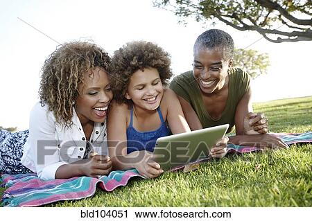 Stock Image - African American family using digital tablet in park. Fotosearch