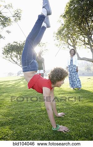 Stock Photograph - African American family watching girl do a handstand. Fotosearch