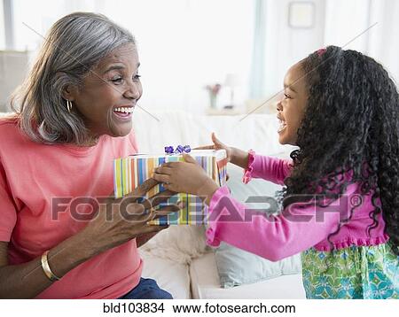 Picture - African American girl giving gift to grandmother. Fotosearch