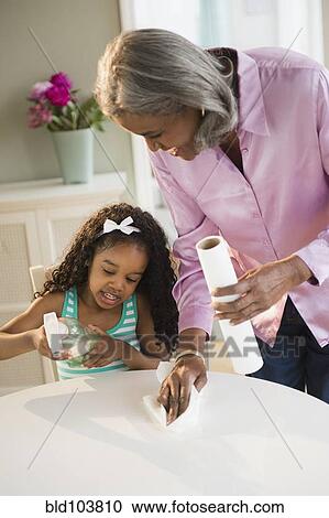 Stock Image - African American grandmother and granddaughter cleaning the table. Fotosearch