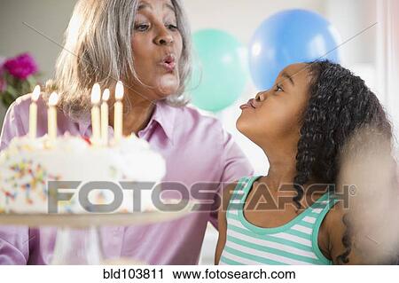 Stock Image - African American grandmother and granddaughter with birthday cake. Fotosearch