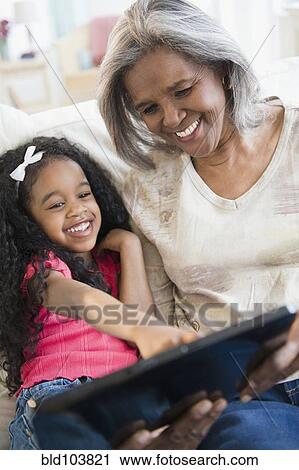 Stock Image - African American grandmother and granddaughter looking at digital tablet. Fotosearch