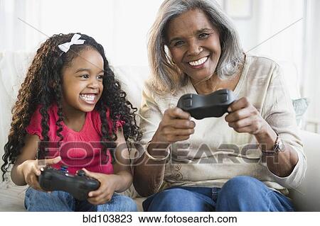 Stock Image - African American grandmother and granddaughter playing video games. Fotosearch