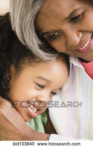 Stock Image - African American grandmother and granddaughter hugging. Fotosearch