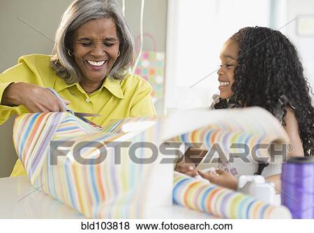 Stock Photo - African American grandmother and granddaughter wrapping gifts. Fotosearch