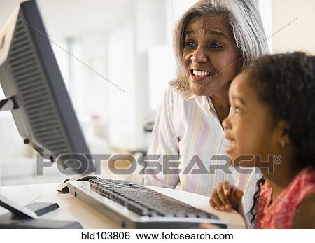Stock Photograph - African American grandmother and granddaughter using computer together. Fotosearch